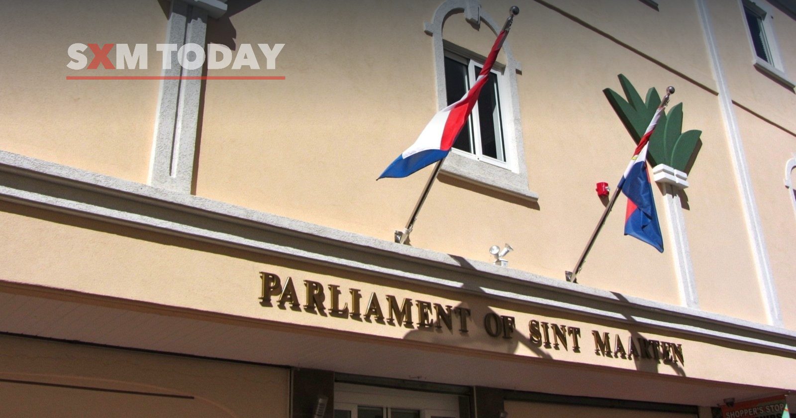 The Parliament of Sint Maarten building in Philipsburg, its name in raised letters beneath the Dutch and Sint Maarten flags.