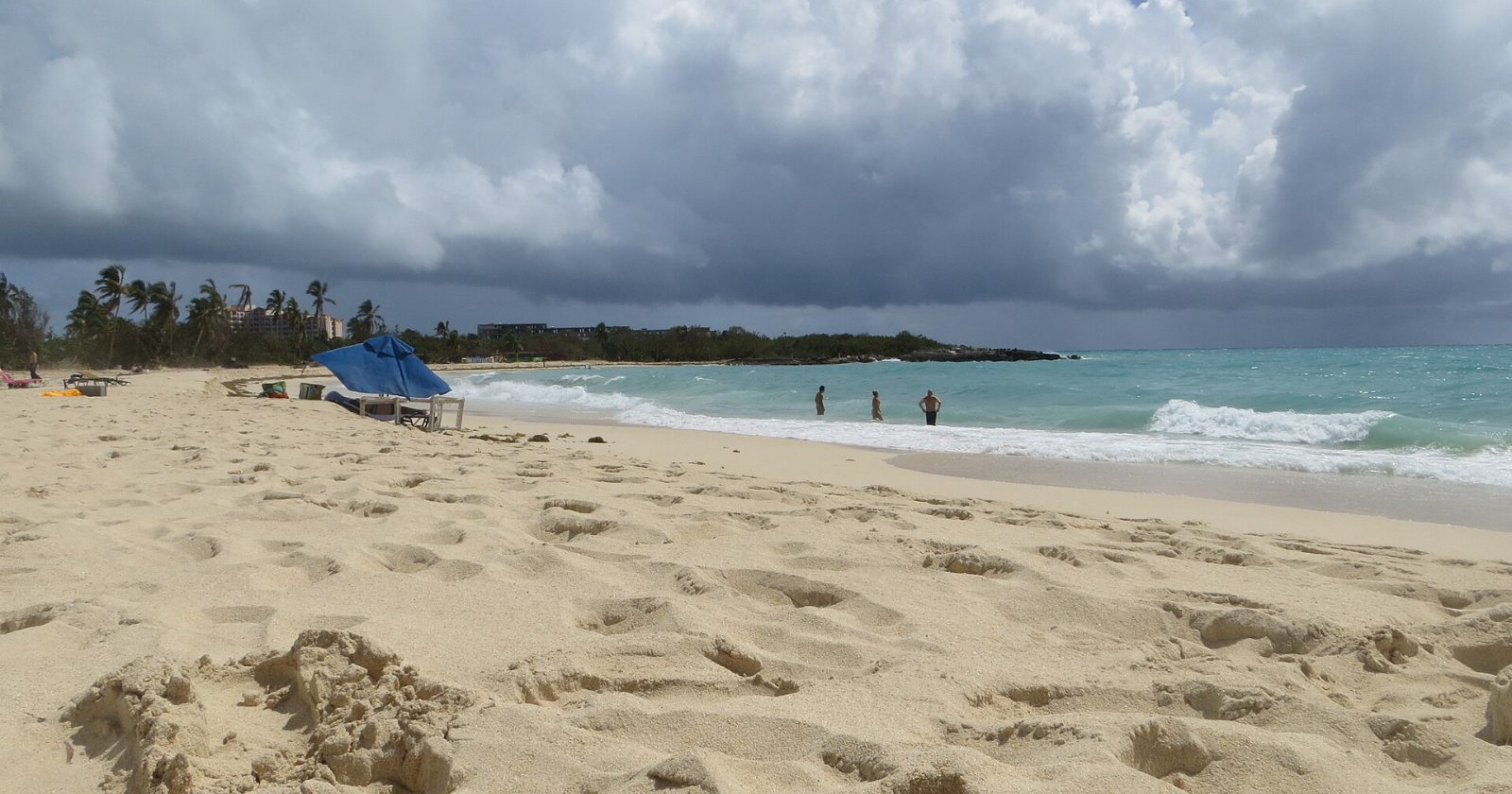 The broad sandy beach at Mullet Bay, Sint Maarten, under a cloudy sky.