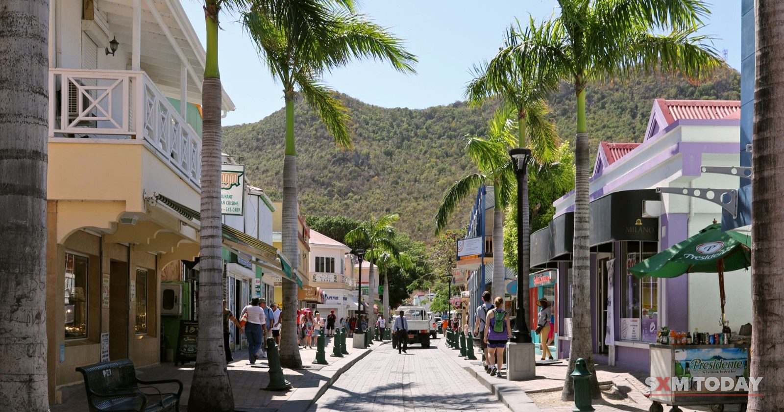 Front Street in Philipsburg, lined with palms and shops, with hills in the distance.