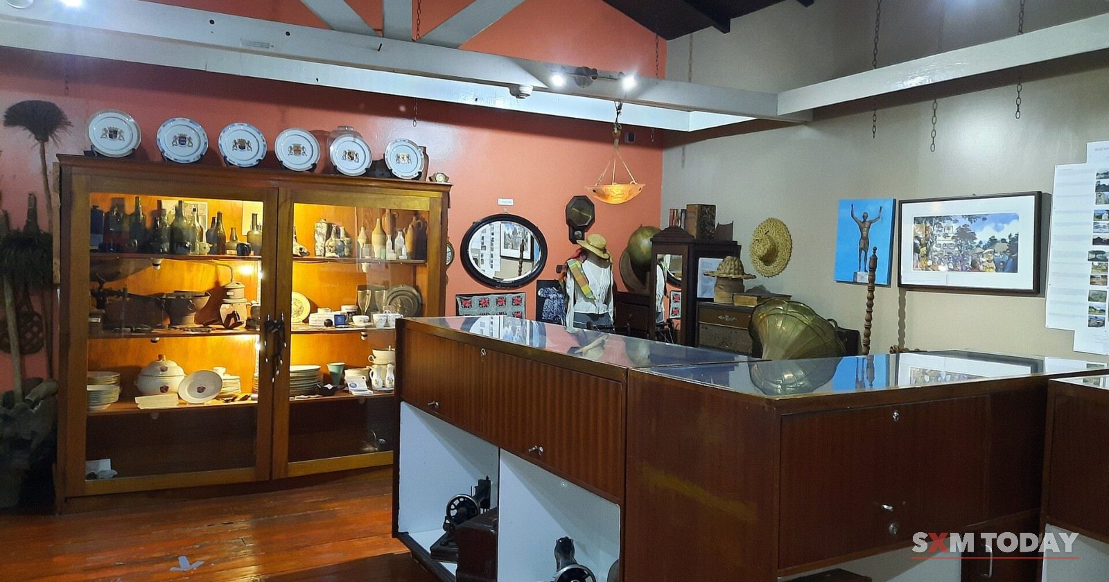 Display cases of old plates, bottles and tools inside the Sint Maarten National Heritage Foundation museum.