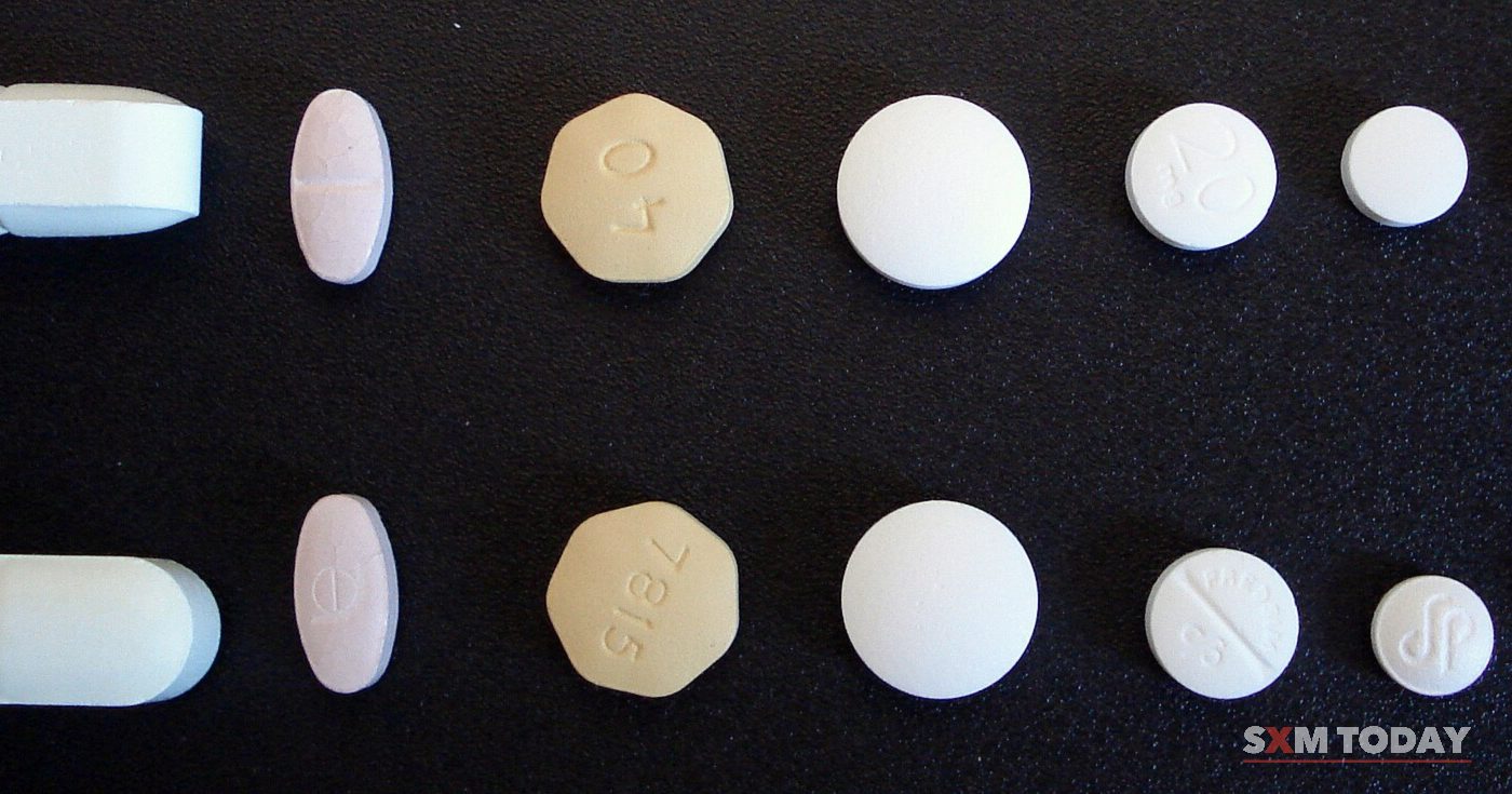 Two rows of tablets of different shapes, sizes and colours laid out on a black background.