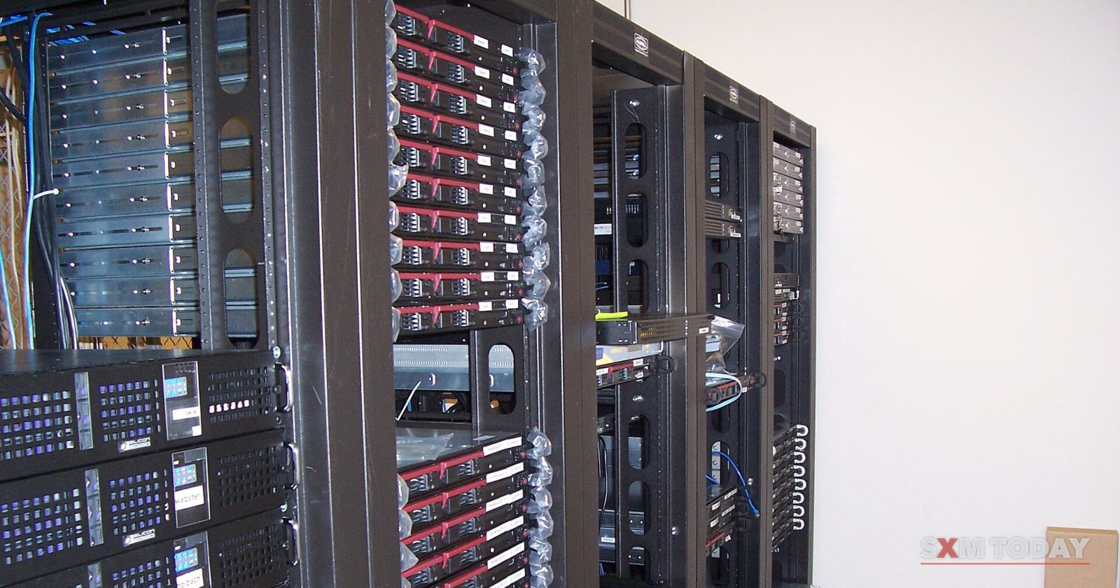 Tall black racks filled with servers and cabling stand side by side in a room.