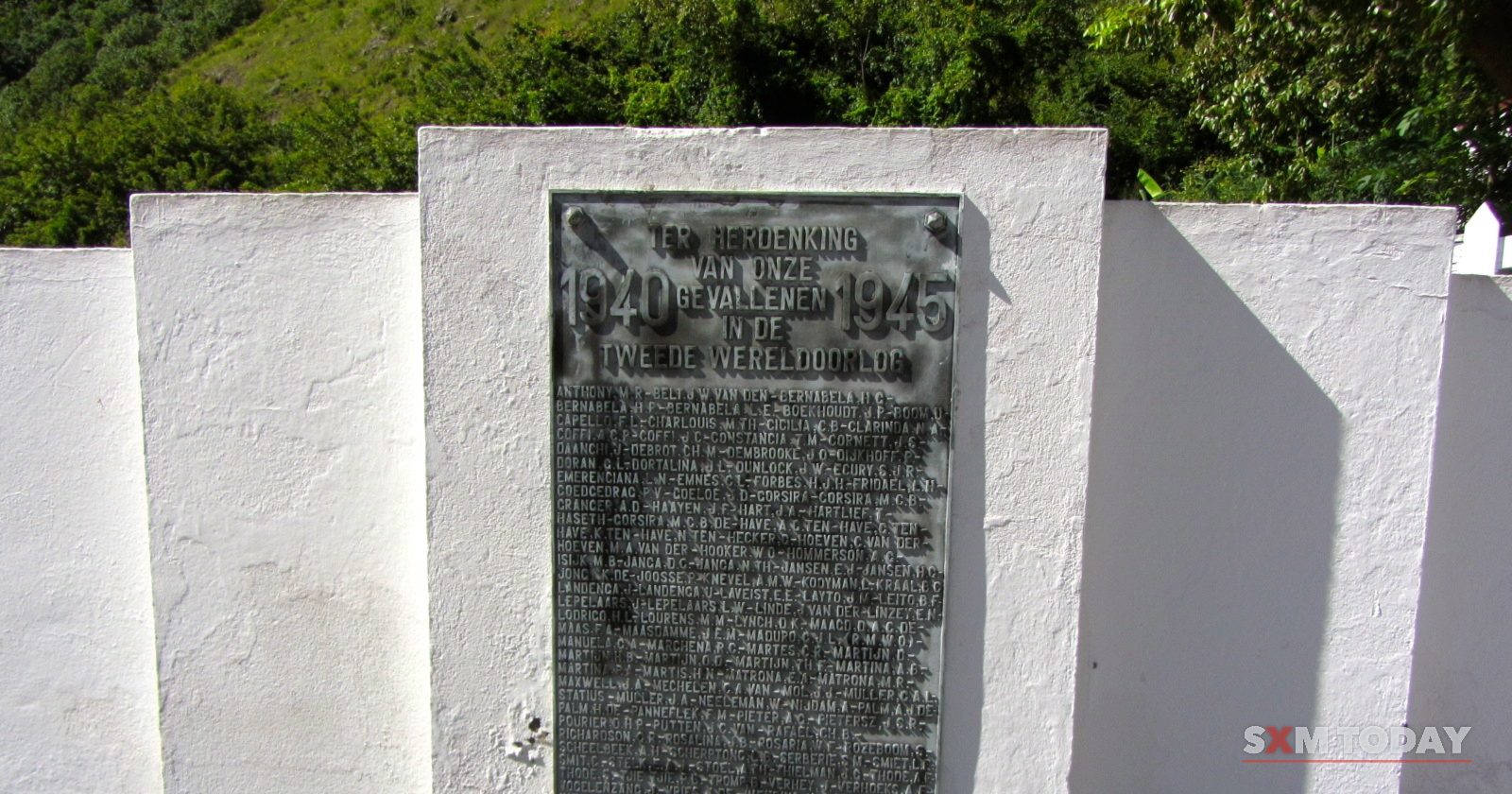 A bronze plaque dated 1940-1945 set into a white-painted stone memorial wall.