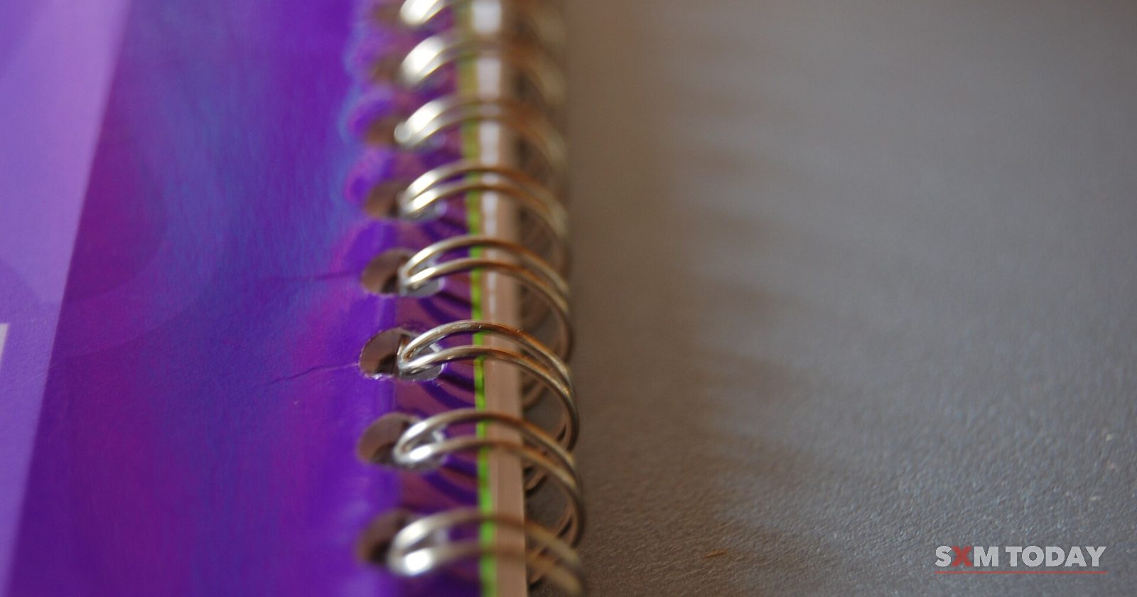 Close-up of the wire spiral binding along the edge of a purple notebook.