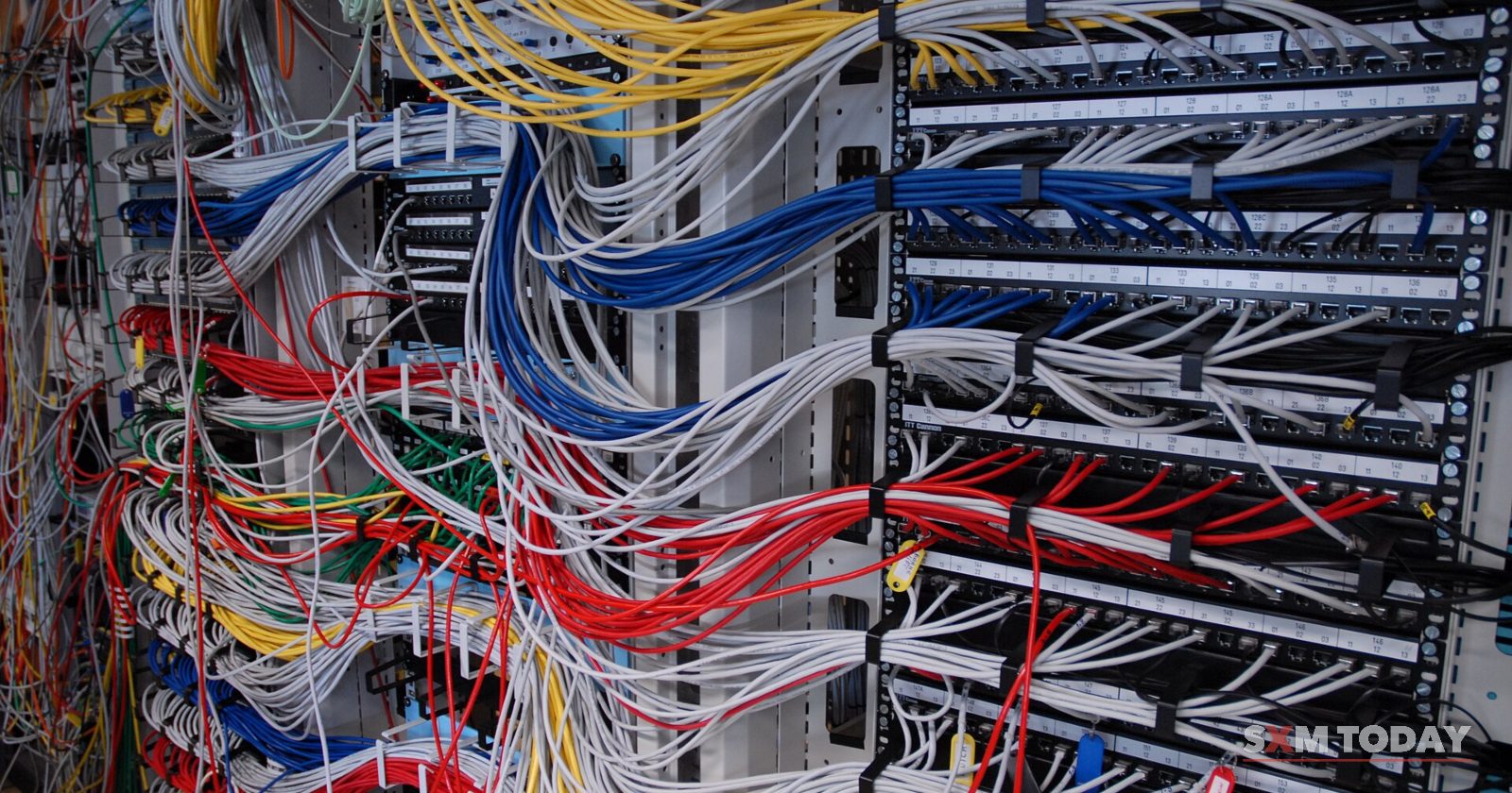 Dense bundles of coloured network cables run into patch panels in a server rack.