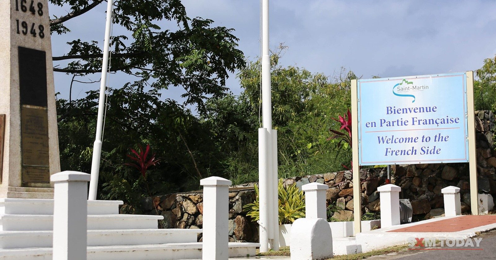 The border monument and a sign reading 'Bienvenue en partie française – Welcome to the French side'.