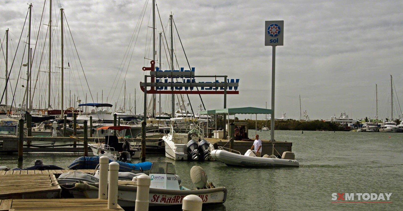 Motorboats tied up at a marina dock on the Simpson Bay Lagoon under a grey sky.