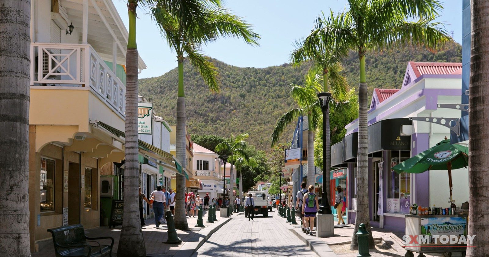 Front Street in Philipsburg, lined with palms and shops, with hills in the distance.