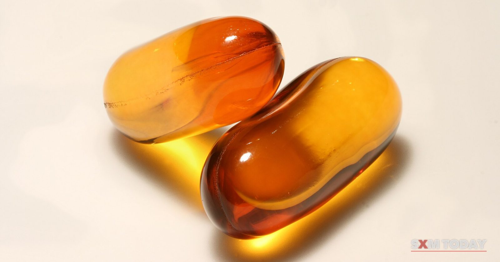 Two translucent amber gel capsules on a pale background.