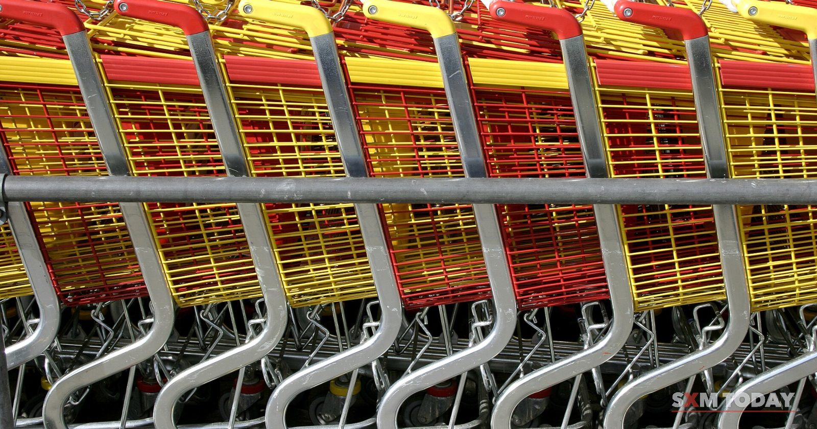 A row of stacked shopping carts with red and yellow plastic baskets.
