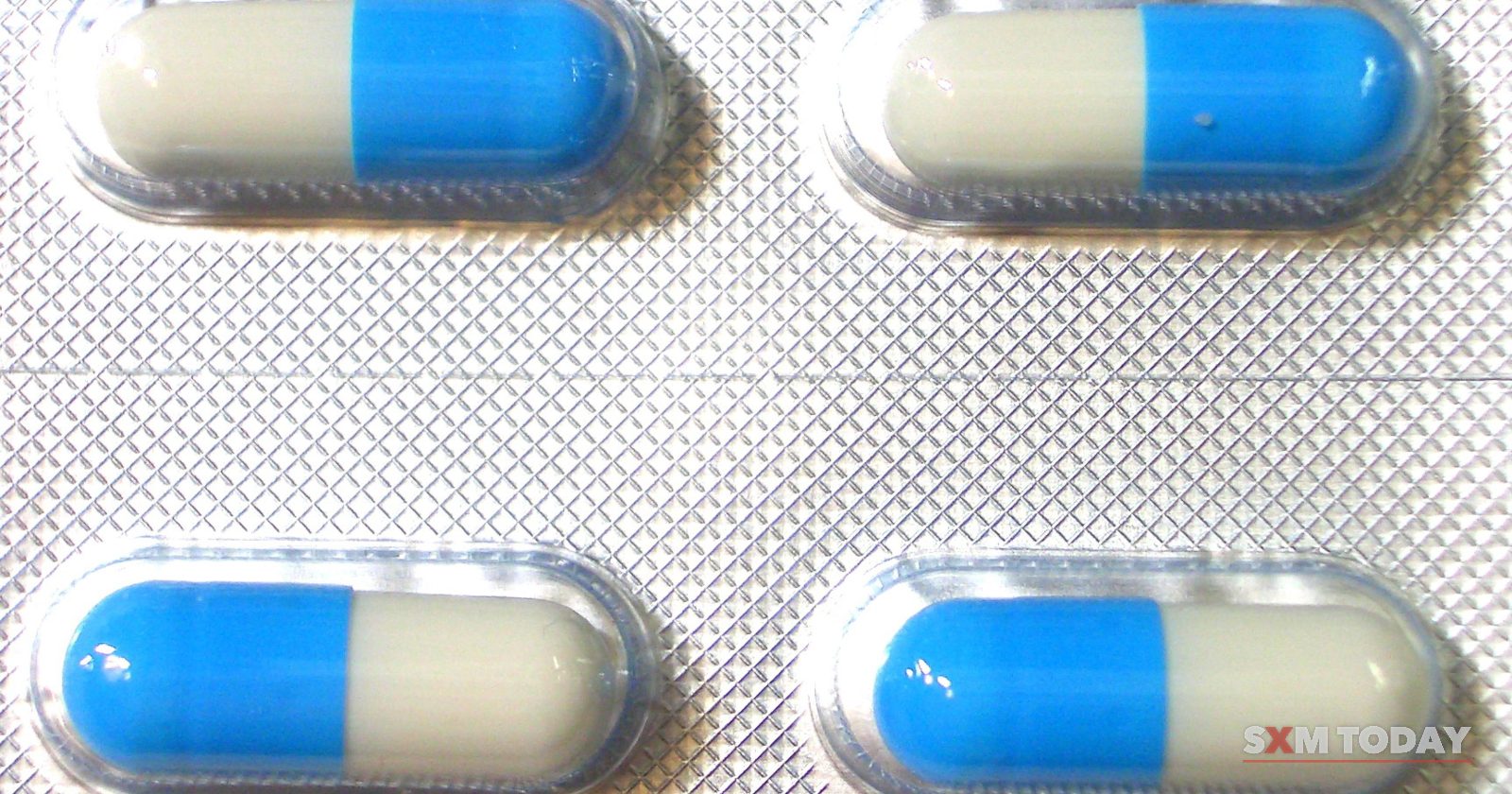 Four blue and white capsules sealed in a blister pack.
