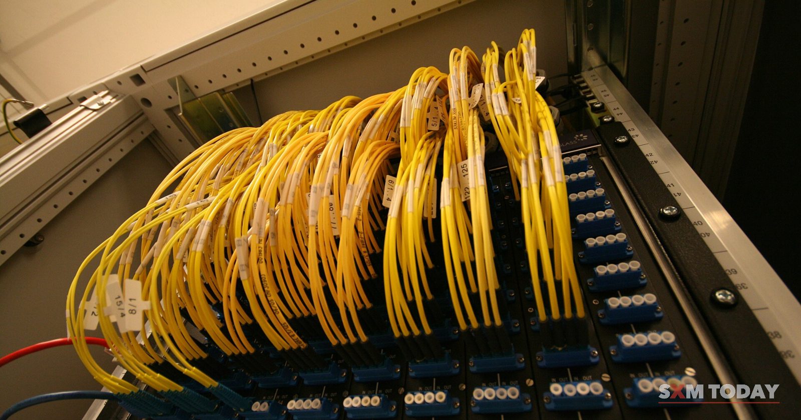 Dozens of yellow fibre-optic cables loop into the ports of a network patch panel.