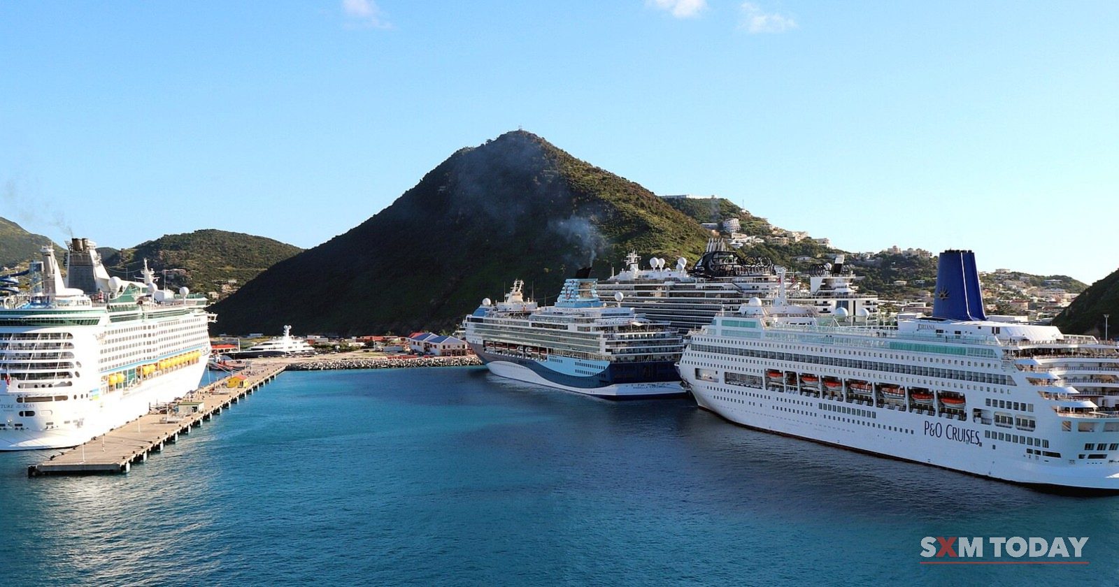 Three cruise ships berthed at the Philipsburg cruise pier, with Sint Maarten's green hills behind.