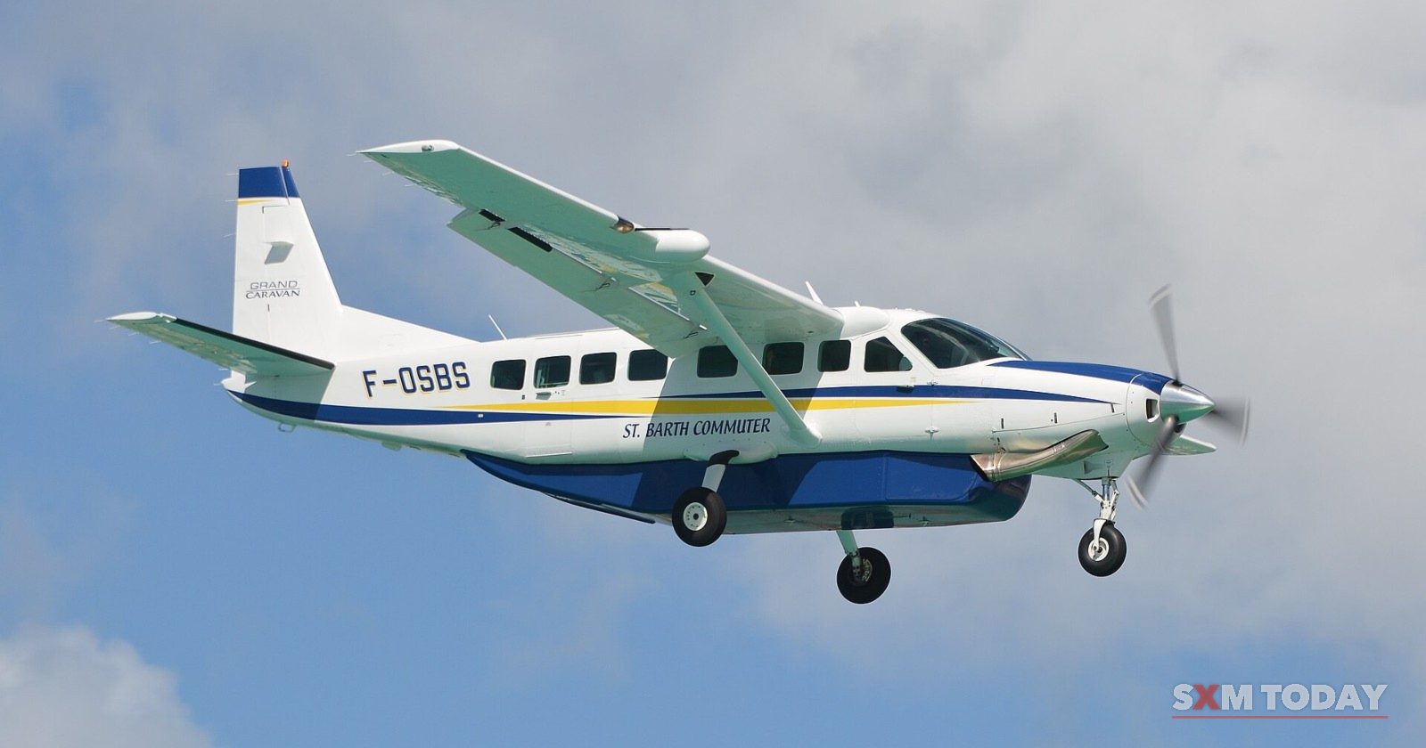 A small passenger plane with its wheels down, approaching Princess Juliana International Airport.