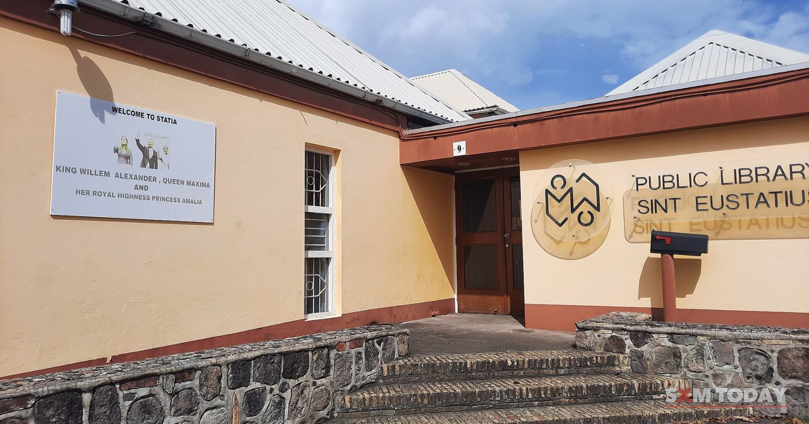 A single-storey library building on a stone base, with steps up to its door and 'Public Library Sint Eustatius' lettered on the wall.