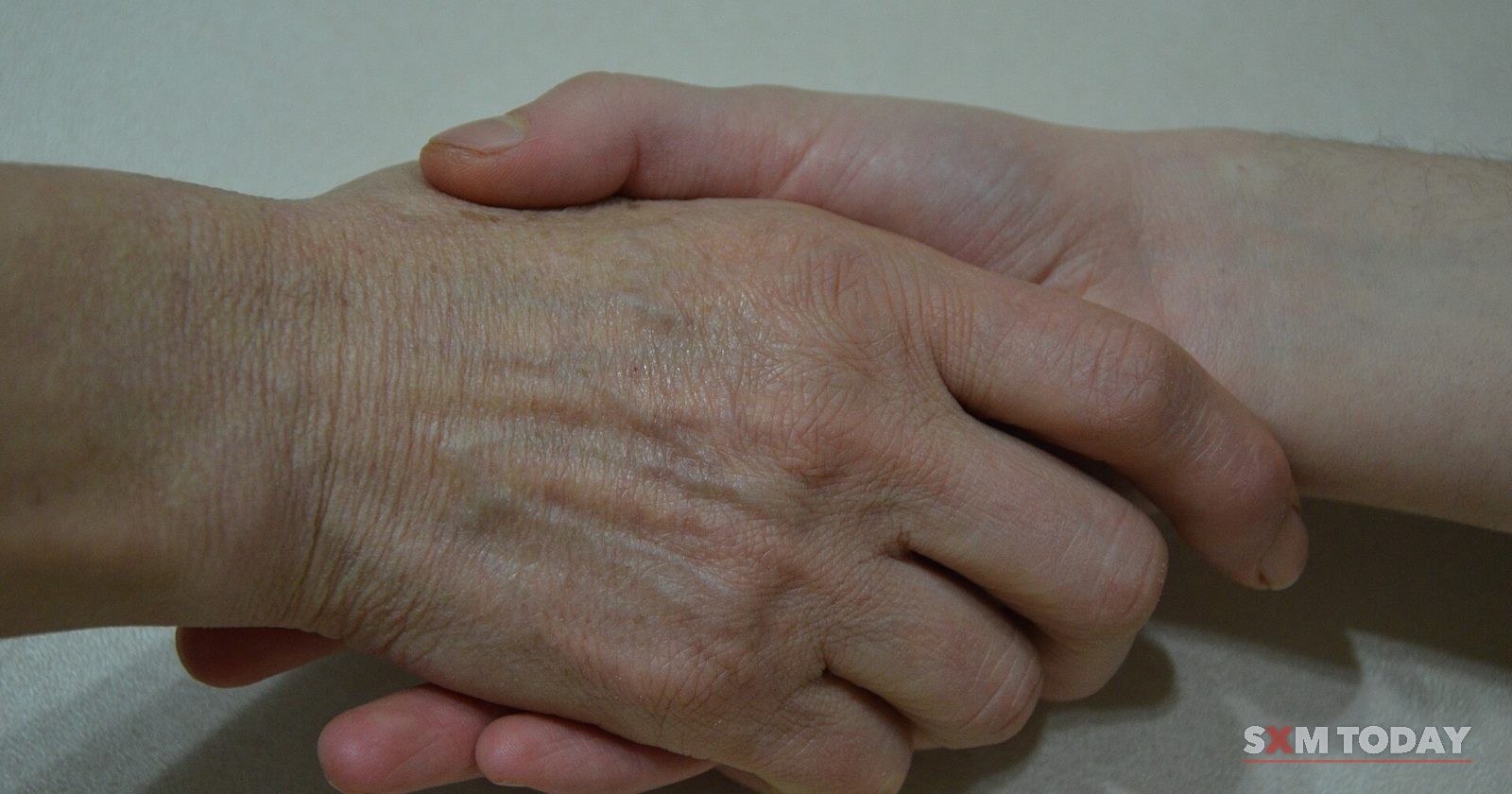 Close-up of an older person's hand resting over a younger person's hand.