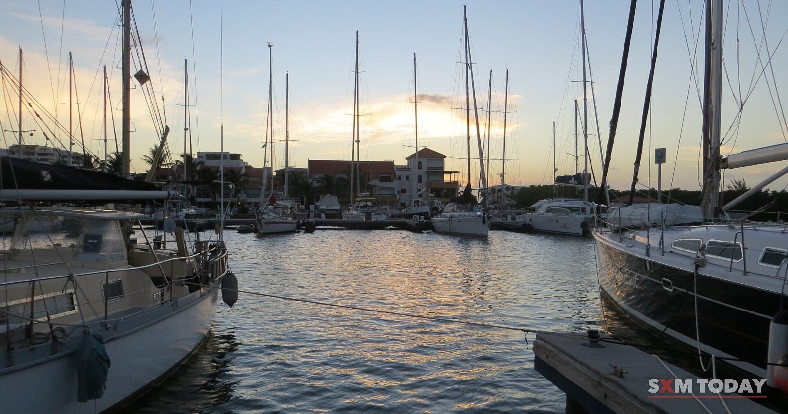 Sailing yachts moored on the calm Simpson Bay Lagoon at dusk.