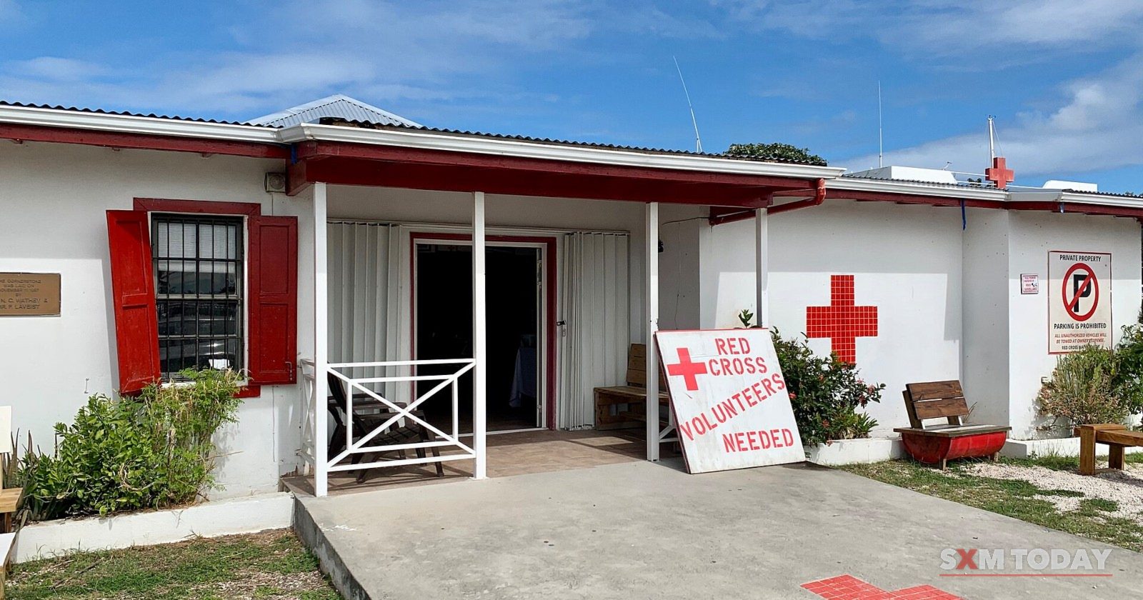 The Sint Maarten Red Cross office, a white building with red shutters and a red cross on the path.