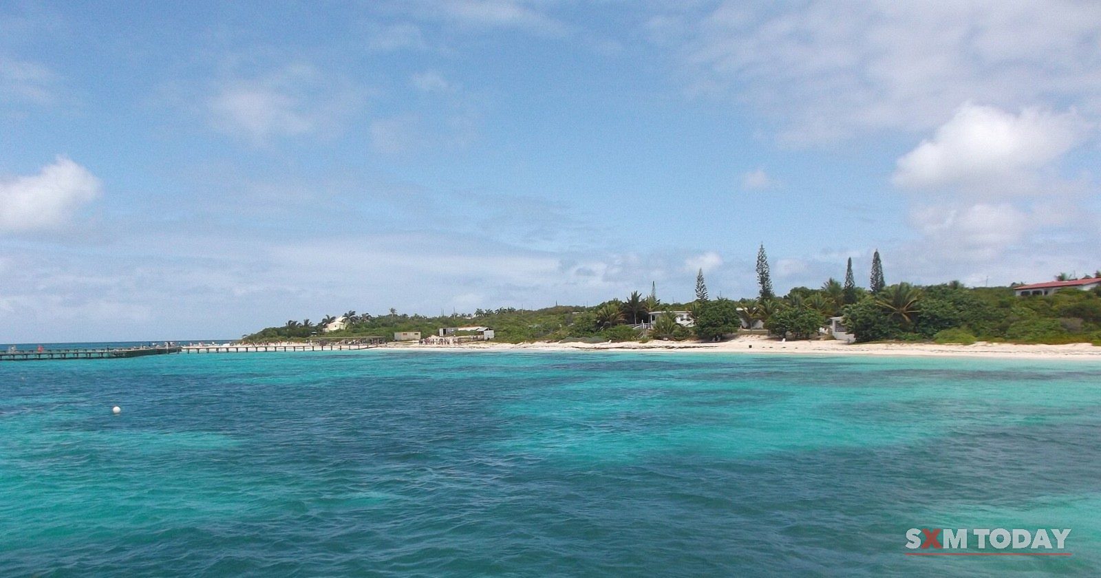 Turquoise water off Blowing Point, Anguilla, with the ferry jetty and the low green shore beyond.