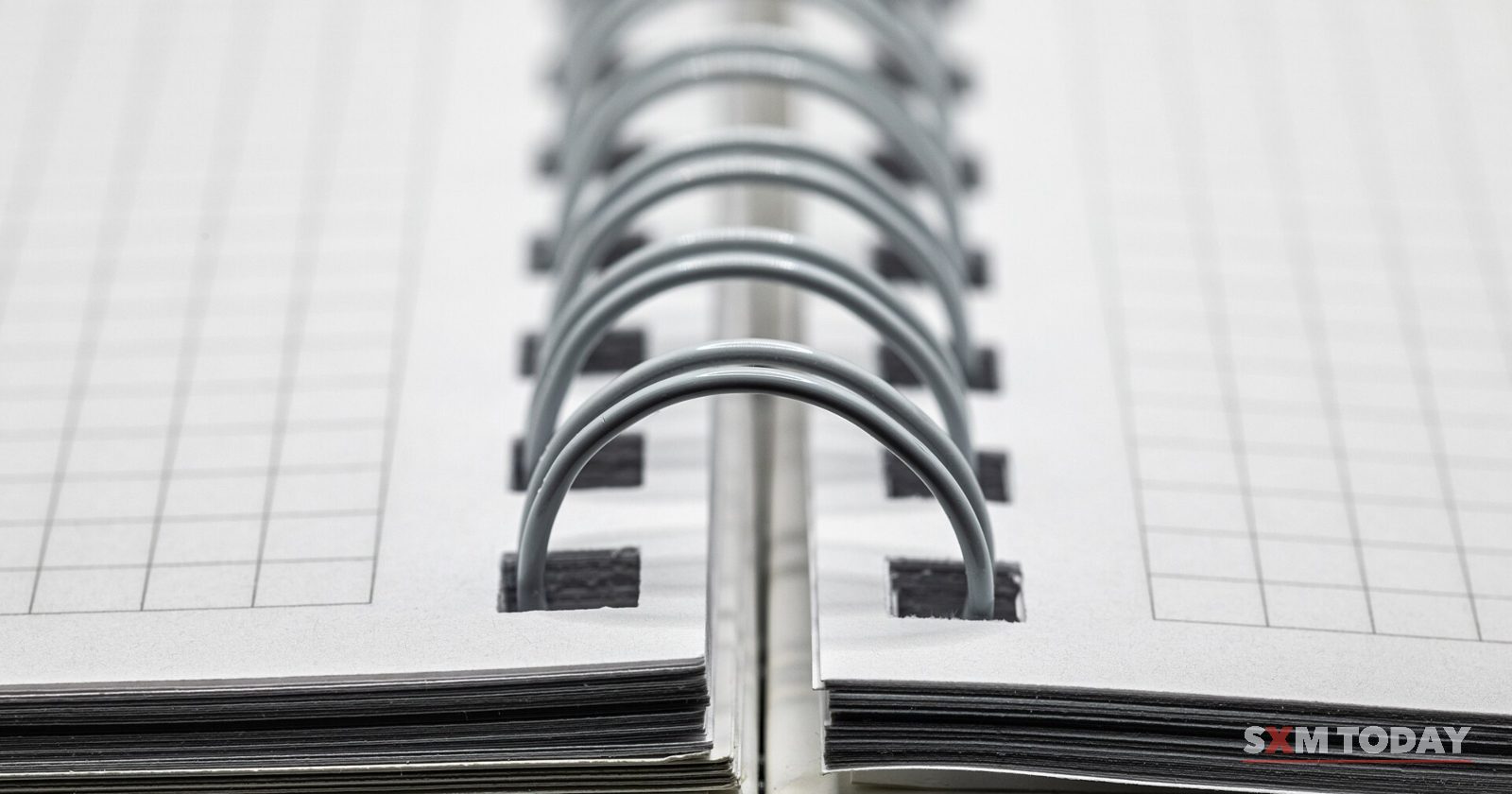 Close-up of the metal spiral binding of an open notebook with grid-lined pages.