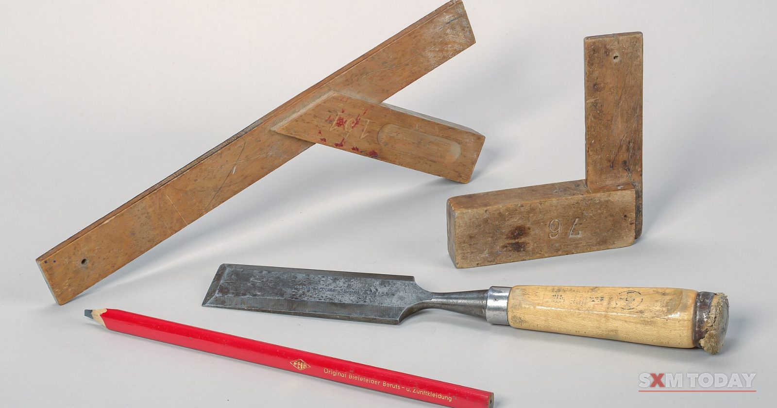 A wood chisel, two wooden squares and a red carpenter's pencil on a pale grey background.