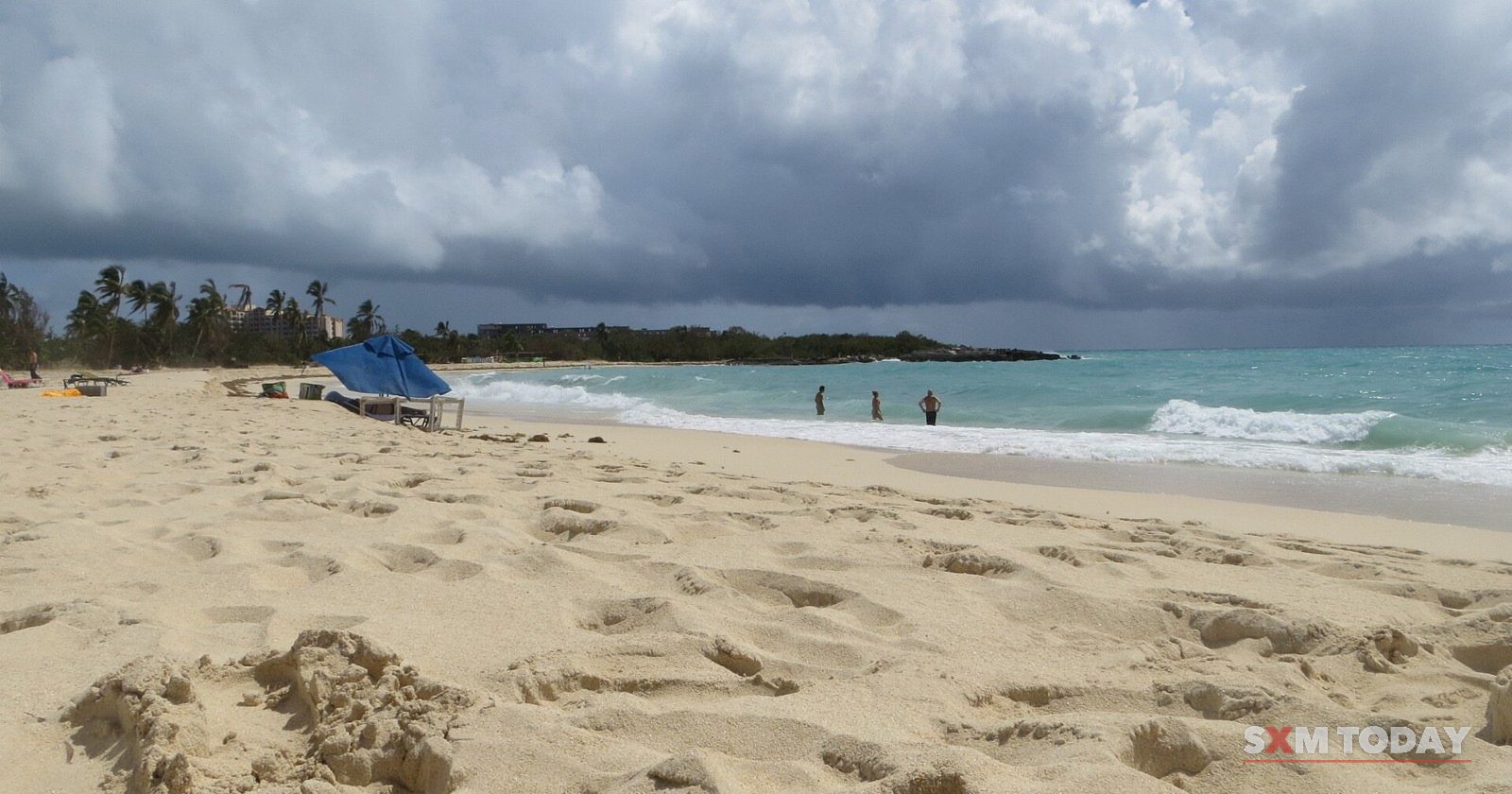 The broad sandy beach at Mullet Bay, Sint Maarten, under a cloudy sky.