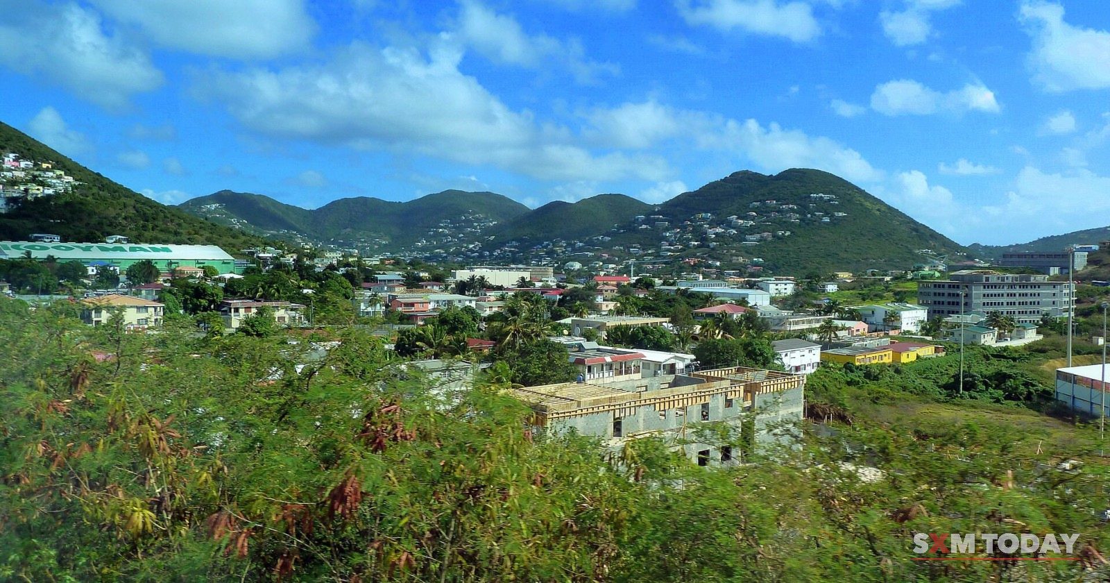 Houses on Cay Hill seen from above, among green hills under a bright sky.