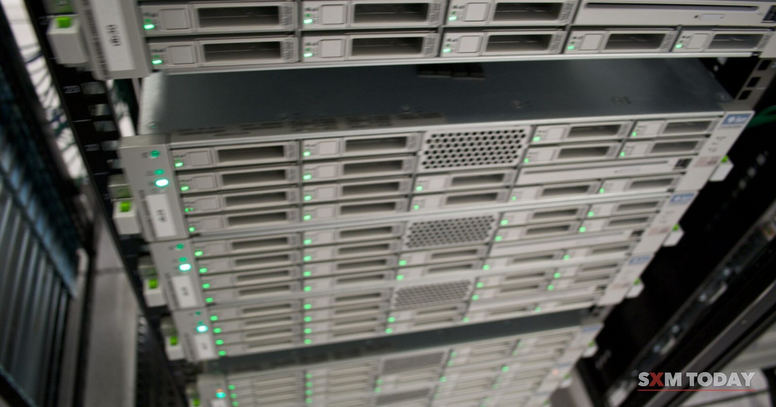 Rows of rack-mounted servers with small green status lights, seen from below.