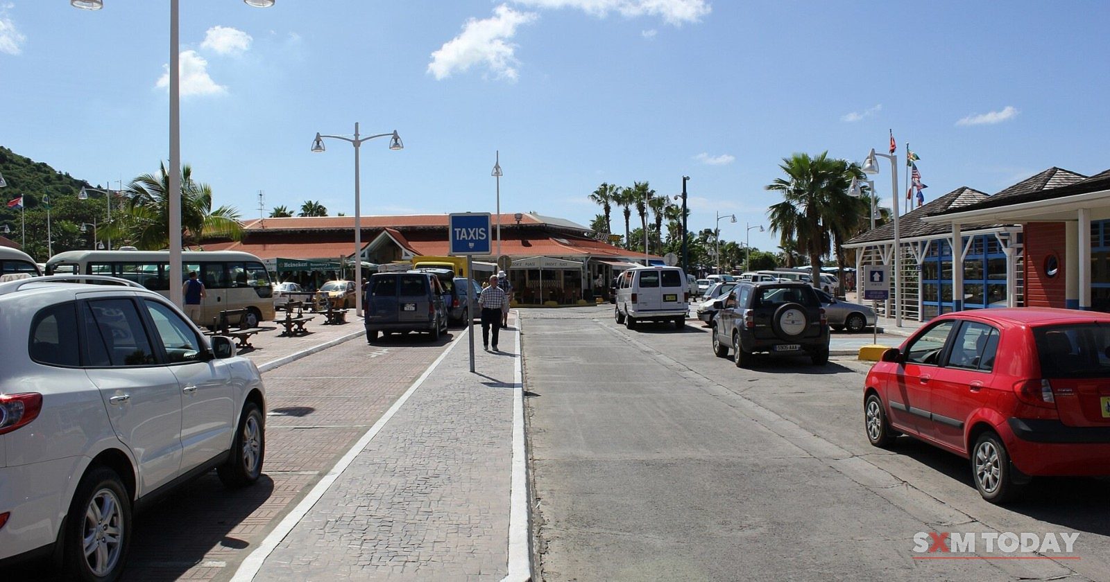 Taxis and cars in the parking area at the Philipsburg cruise facility, under a blue sky.