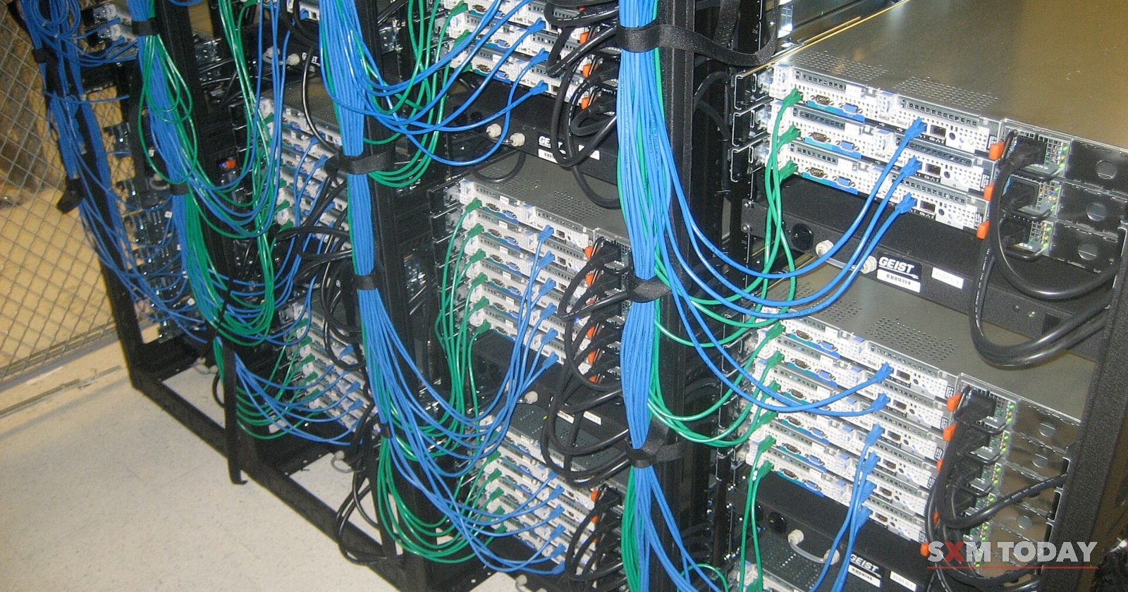 Rows of rack-mounted servers with blue and green network cables bundled down the side.