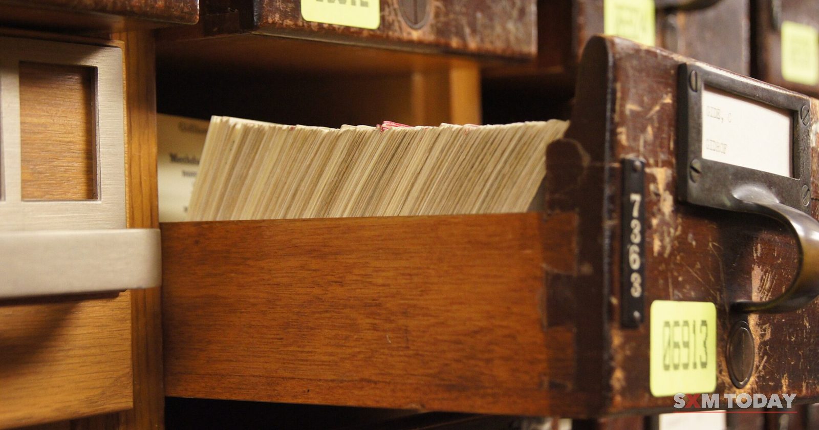 An open wooden drawer packed with index cards, between numbered drawers.