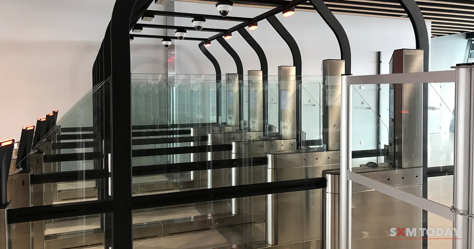 A row of empty glass automated passport control gates in an airport hall.