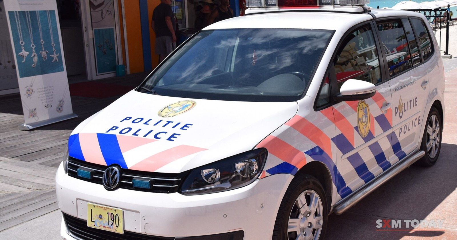 A Sint Maarten police patrol car in white, with blue and red Politie Police markings, parked in the sun.