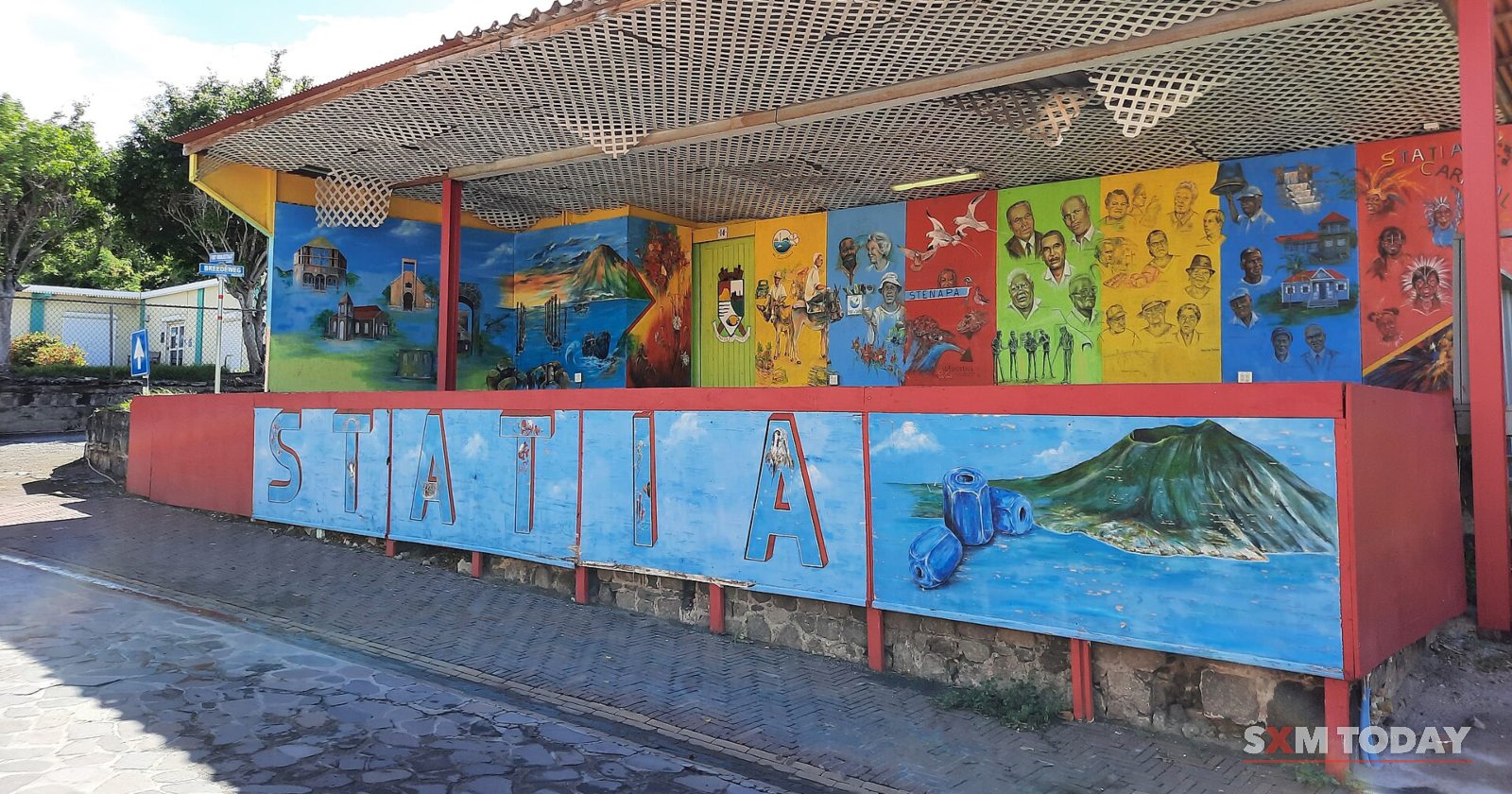 A covered open-air stage is painted with colourful murals of sea life and the island above large letters spelling 'Statia'.