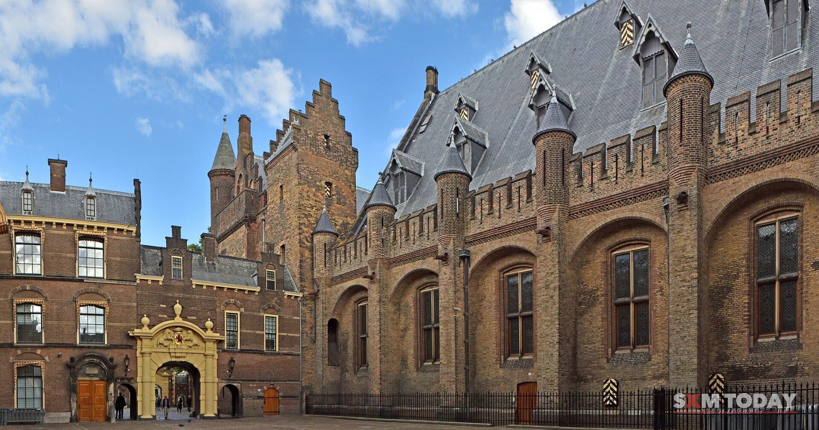The brick Ridderzaal and surrounding buildings of the Binnenhof, The Hague, under a blue sky.