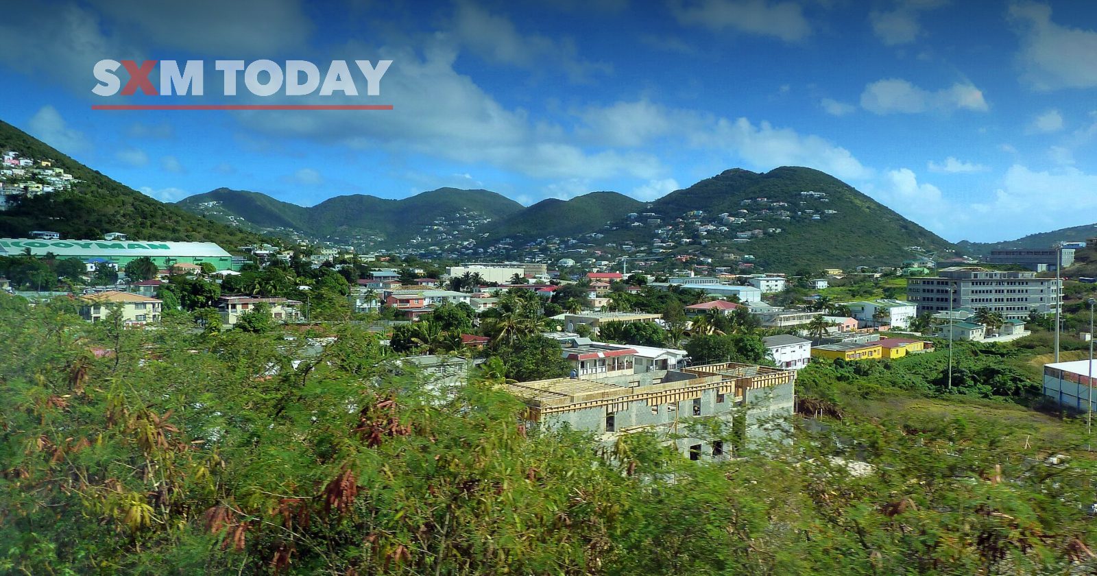 Houses on Cay Hill seen from above, among green hills under a bright sky.