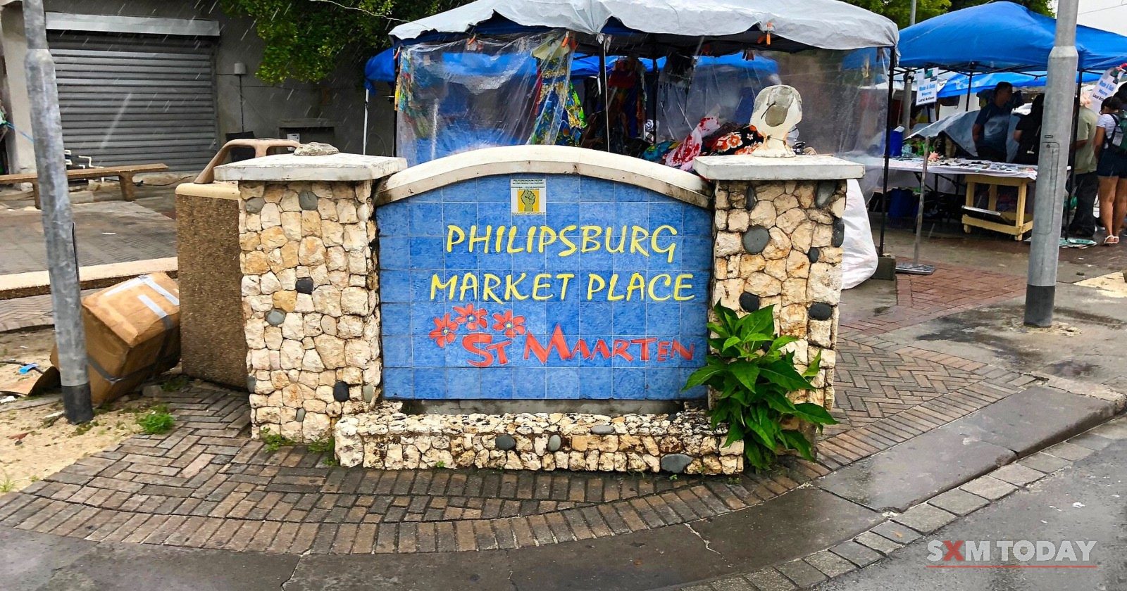 The stone Philipsburg Market Place sign in front of vendors' tents.