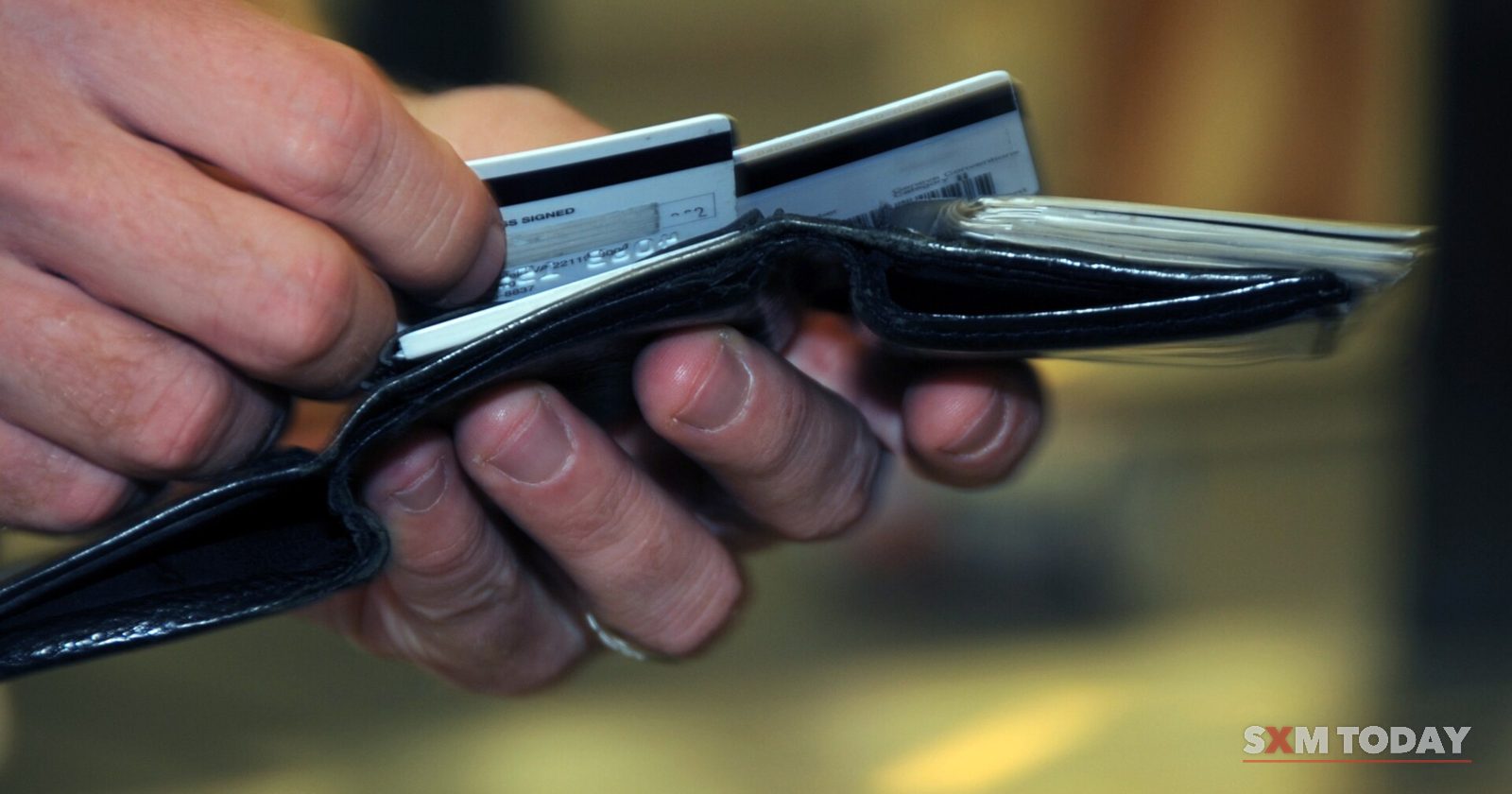 Close-up of hands holding an open black wallet and drawing out a bank card.